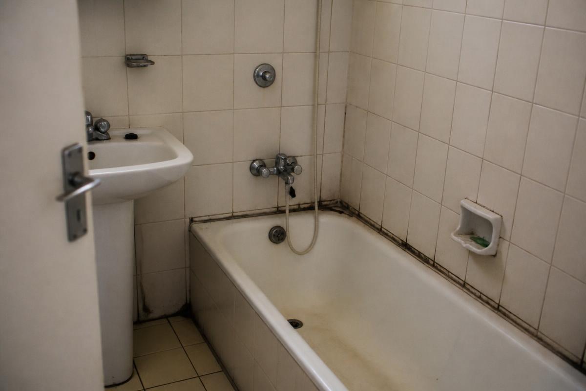 Badkamer particulier voor de reparatie: aangetaste kit, versleten voegwerk en losse tegels
